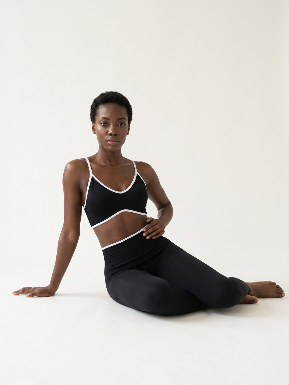 Black · Signature Contrast Set noir, assise au sol jambes repliées
