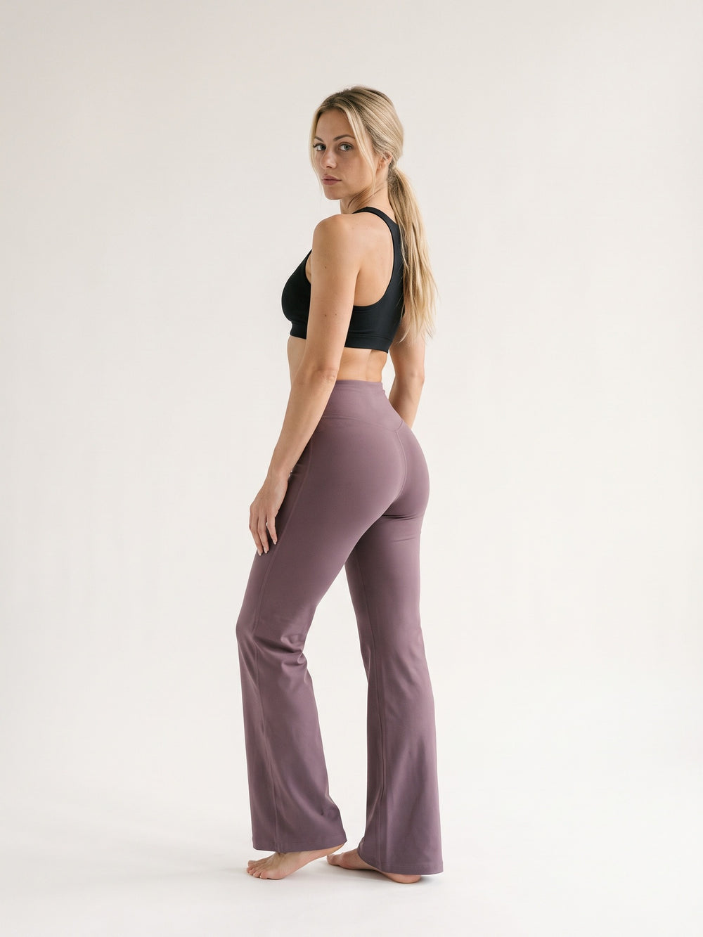 Flow Flare Leggings mauve vu de dos, buste tourné vers la caméra